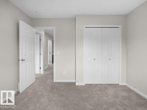 Plush carpeted flooring with light neutral wall tones, a paneled door, and bi-fold closet doors - 2039 13 Avenue, Edmonton, AB 