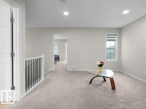 Spacious carpeted upper-level area featuring recessed lighting, a white baluster with black iron spindles, and a window with blinds - 2039 13 Avenue, Edmonton, AB 