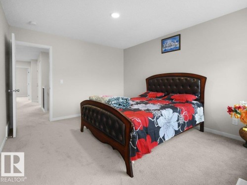 Carpeted bedroom featuring light neutral wall paint, recessed lighting, and a doorway opening to a hallway - 2039 13 Avenue, Edmonton, AB 