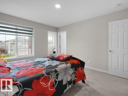 Bedroom featuring a large window with horizontal blinds, neutral wall paint, recessed lighting, white trim, and carpet flooring - 