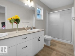 Dual sink vanity with white cabinetry and dark hardware, set against light neutral walls - 