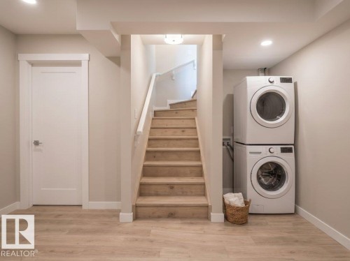 Laundry area featuring a stacked washer and dryer, wood-finish flooring, and recessed ceiling lighting - 2039 13 Avenue, Edmonton, AB 