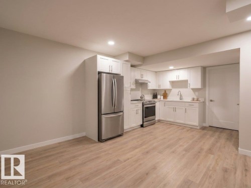 Kitchen featuring white shaker cabinetry, stainless steel appliances, wood-finish flooring, recessed lighting, and a neutral color palette - 2039 13 Avenue, Edmonton, AB 