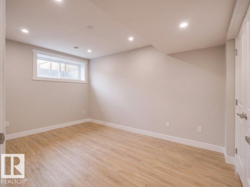 Bright room featuring light wood-finish flooring, recessed lighting, a horizontal window with white trim, and a paneled door - 2039 13 Avenue, Edmonton, AB 