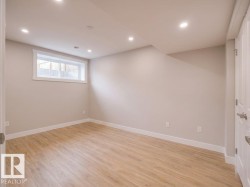 Bright room featuring light wood-finish flooring, recessed lighting, a horizontal window with white trim, and a paneled door - 