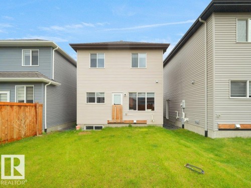 Rear exterior featuring light-colored vinyl siding, a walk-out deck, and multiple windows - 2039 13 Avenue, Edmonton, AB 