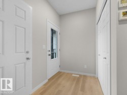 Entryway featuring wood-finish flooring, light grey walls, white trim, and a full-light panel door - 