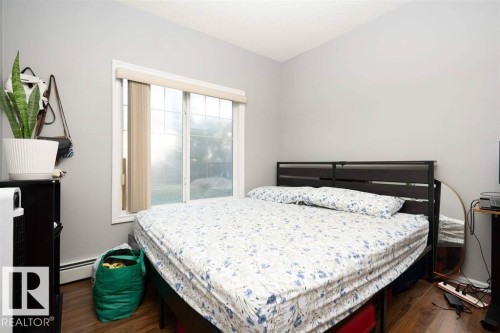 Room featuring a window with vertical blinds, wood-finish flooring, and light-toned walls - #117 226 Macewan Sw, Edmonton, AB - Indoor Photo Showing Bedroom