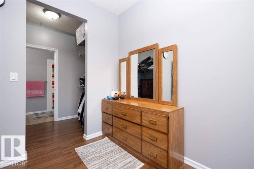 Interior hallway featuring wood-finish flooring, light grey walls, and white baseboards - #117 226 Macewan Sw, Edmonton, AB - Indoor