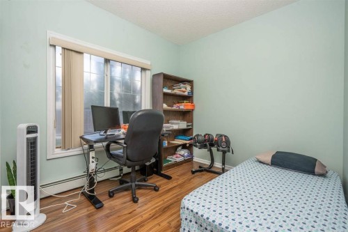 Room featuring wood-finish flooring, a window with blinds, and light green walls - #117 226 Macewan Sw, Edmonton, AB - Indoor Photo Showing Bedroom