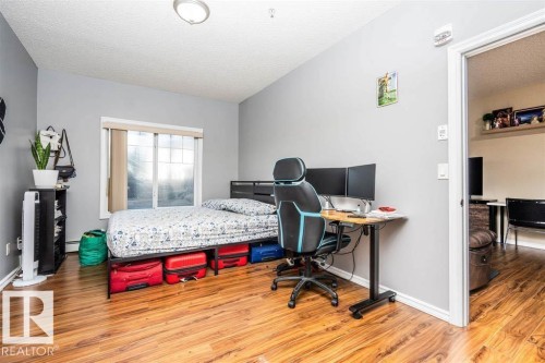 Room featuring wood-finish flooring, light grey painted walls, and a window with blinds - #117 226 Macewan Sw, Edmonton, AB - Indoor