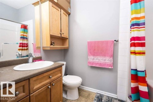 Bathroom featuring a vanity with an oval sink and a brown countertop, light wood cabinetry, and a wall-mounted medicine cabinet - #117 226 Macewan Sw, Edmonton, AB - Indoor Photo Showing Bathroom