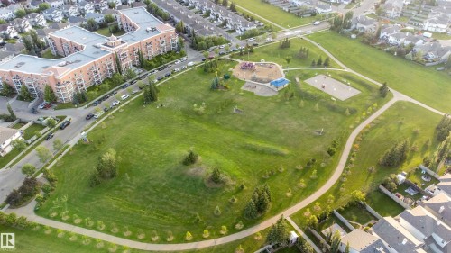 Expansive green space featuring walking paths, mature trees, a children's play area, and sports courts - #117 226 Macewan Sw, Edmonton, AB -  With View