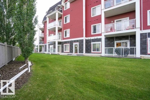 Ground-level patio with glass railing and a dark wood-finish deck - #117 226 Macewan Sw, Edmonton, AB - Outdoor