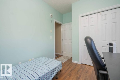 Room featuring wood-finish flooring, a light blue wall color, white trim, and a white bi-fold closet door - #117 226 Macewan Sw, Edmonton, AB - Indoor