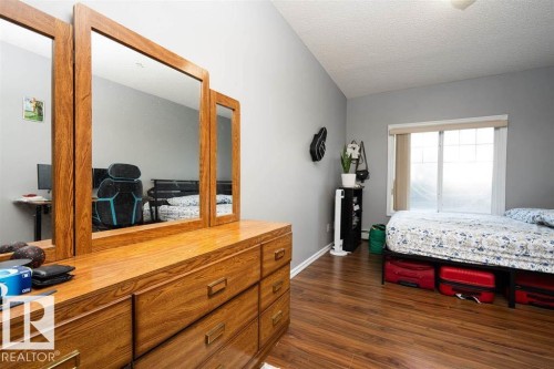 Spacious room featuring wood-finish flooring, a vaulted ceiling, and neutral gray walls - #117 226 Macewan Sw, Edmonton, AB - Indoor Photo Showing Bedroom