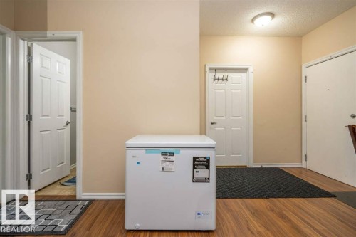 Warm-toned walls complement wood-finish flooring throughout this area - #117 226 Macewan Sw, Edmonton, AB - Indoor Photo Showing Other Room
