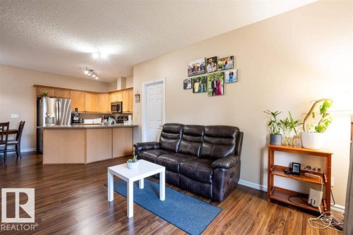 Open concept living space featuring wood-finish flooring, a kitchen with light wood cabinetry and stainless steel appliances, and a breakfast bar - #117 226 Macewan Sw, Edmonton, AB - Indoor Photo Showing Other Room
