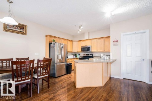 Kitchen and dining area featuring wood-finish flooring - #117 226 Macewan Sw, Edmonton, AB - Indoor
