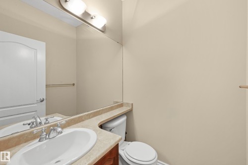 Bathroom featuring an oval undermount sink, dual-handle faucet, integrated countertop, wood-finish vanity, and a large wall-mounted mirror - 11544 11 Avenue, Edmonton, AB 