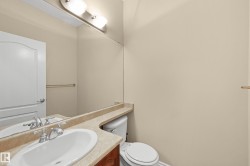 Bathroom featuring an oval undermount sink, dual-handle faucet, integrated countertop, wood-finish vanity, and a large wall-mounted mirror - 