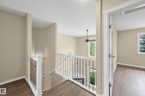 Open landing featuring wood-finish flooring, white trim, and a staircase with white newel posts and dark metal balusters - 11544 11 Avenue, Edmonton, AB 