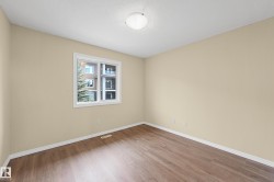 Bright room featuring wood-finish flooring, light-toned walls, a white trim window, a ceiling-mounted light fixture, and white baseboards - 