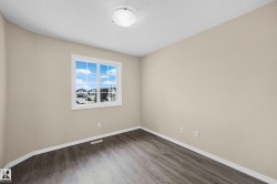 Neutral-toned room featuring a large window, dark wood-finish flooring, white baseboards, and a flush-mount ceiling light fixture - 