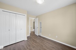 Interior room featuring wood-finish flooring, light tan wall paint, and white baseboards - 