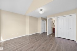 Spacious room featuring wood-finish flooring, neutral-toned walls, and white baseboards - 