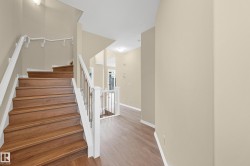 Staircase with wood-finish treads and risers, featuring a white painted handrail with metal balusters - 