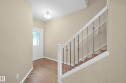 Entryway featuring wood-finish flooring, a white paneled door with decorative glass, and a flush mount ceiling light - 