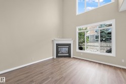 Vaulted ceilings with high windows, wood-finish flooring, and a corner fireplace with a white mantel and dark tile surround - 