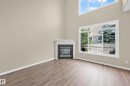 Vaulted ceilings with high windows, wood-finish flooring, and a corner fireplace with a white mantel and dark tile surround - 11544 11 Avenue, Edmonton, AB 