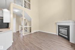 Living area featuring wood-finish flooring, a corner fireplace with a white mantel, and high ceilings - 