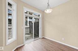 Interior room featuring wood-finish flooring, light beige wall paint, and white baseboards - 
