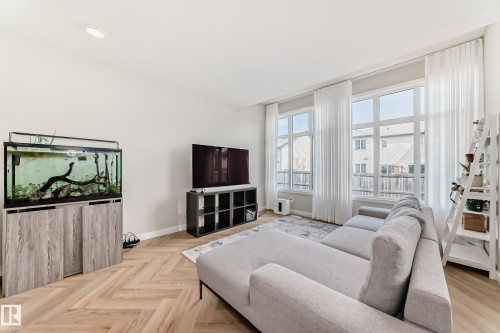 Bright living area featuring wood-finish flooring in a herringbone pattern - 4231 206 Street, Edmonton, AB 
