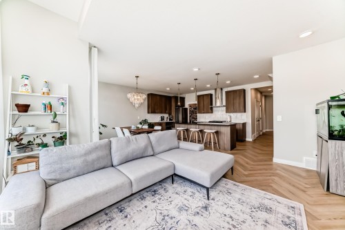 Open-concept living area featuring wood-finish herringbone flooring, recessed lighting, and a vaulted ceiling - 4231 206 Street, Edmonton, AB 