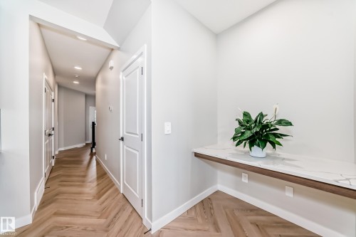 Herringbone wood-finish flooring extending through a bright hallway with recessed lighting - 4231 206 Street, Edmonton, AB 
