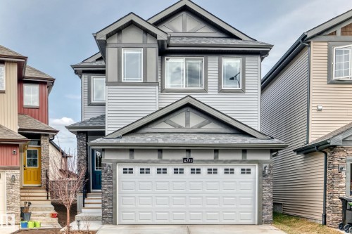 Three-story residence featuring light gray horizontal siding, dark gray trim, and stone veneer accents - 4231 206 Street, Edmonton, AB 