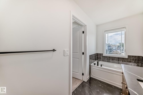 Bathroom featuring a built-in bathtub with black fixtures, dark subway tile surround, and a large window - 4231 206 Street, Edmonton, AB 