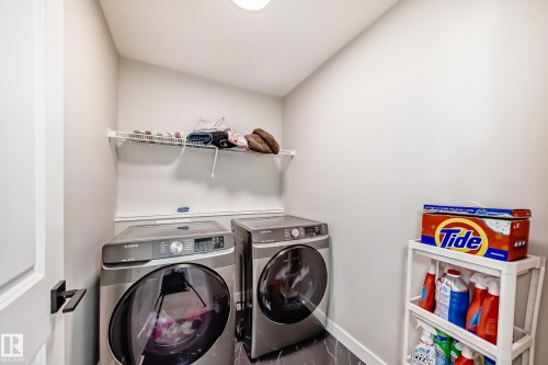 Dedicated laundry area featuring a white wire shelf, crown molding, and dark-toned flooring - 4231 206 Street, Edmonton, AB 