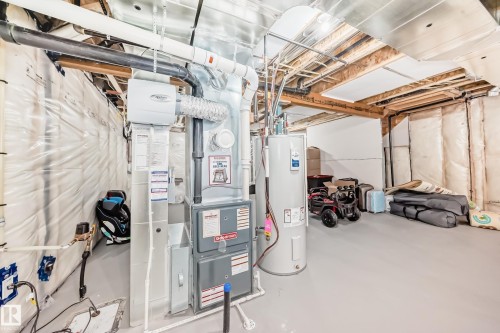 Utility space featuring a water heater, furnace, and exposed ceiling joists - 4231 206 Street, Edmonton, AB 