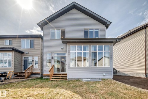 Rear exterior featuring a sunroom addition with multiple windows, a sliding glass door, and a wooden deck - 4231 206 Street, Edmonton, AB 
