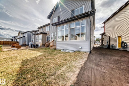 Two-story residence with light gray siding, large upper-level windows, and a sunroom extension featuring multiple windows - 4231 206 Street, Edmonton, AB 