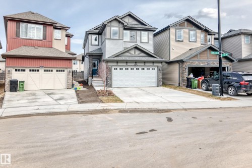 Two-story residence featuring a light gray and white exterior with stone accents and a prominent front-facing garage - 4231 206 Street, Edmonton, AB 
