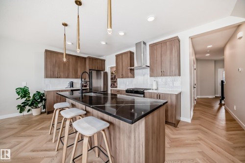 Modern kitchen featuring a large central island with a dark countertop and breakfast bar seating - 4231 206 Street, Edmonton, AB 