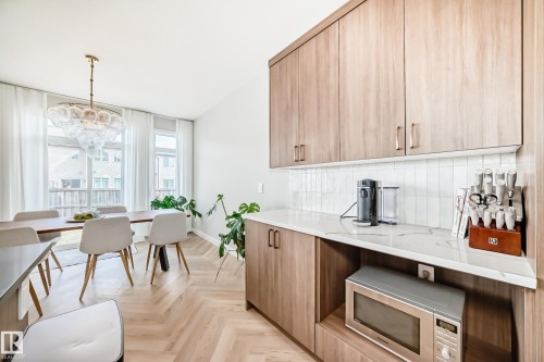 Kitchenette and dining area featuring wood-finish cabinetry, white subway tile backsplash, white countertops, and herringbone-patterned wood-finish flooring - 4231 206 Street, Edmonton, AB 