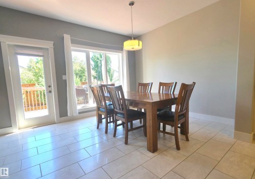 Spacious room featuring light-toned tile flooring, a large window, and a glass-paneled door opening to an outdoor deck - 1 Hemlock Close, Fort Saskatchewan, AB 