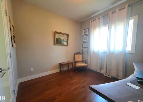 Hardwood flooring throughout featuring baseboard trim, neutral wall color, and a window with white trim - 1 Hemlock Close, Fort Saskatchewan, AB 